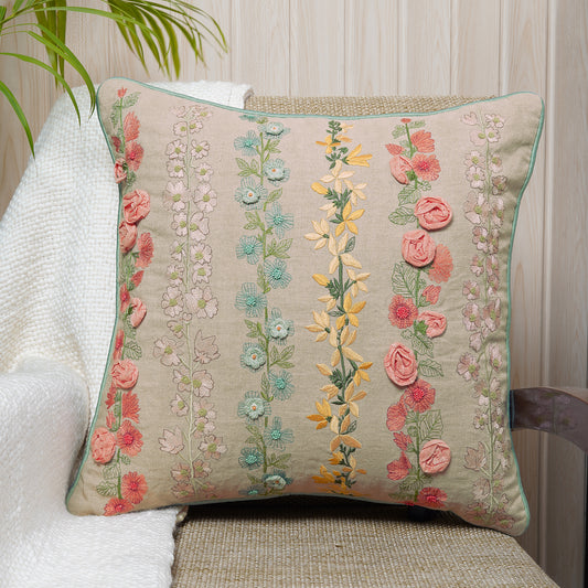 Decorative embroidered floral cushion in multicolor on a beige fabric.