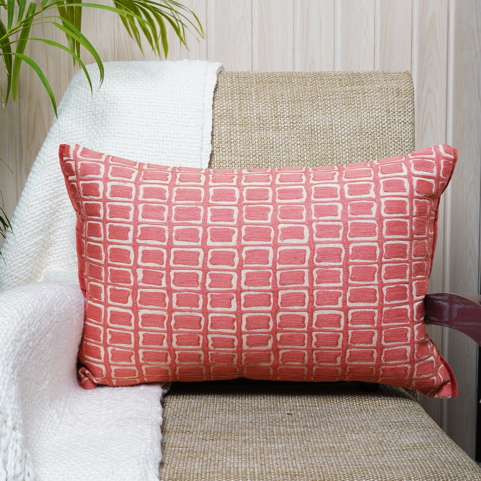 Hand-embroidered rectangular cushion with rose blush geometric design on a neutral beige background