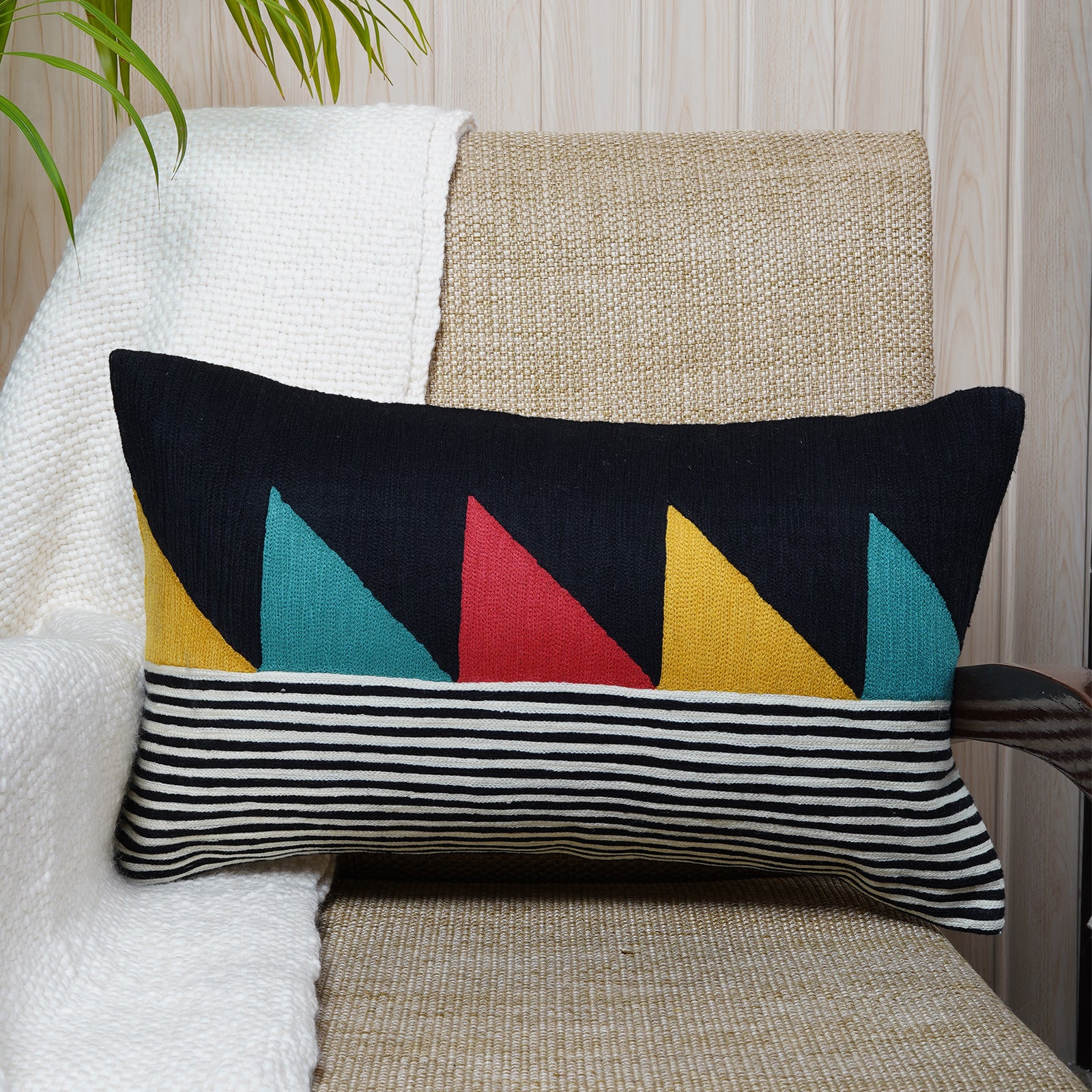Rectangular black cushion with bold colourblock triangles and monochrome stripes